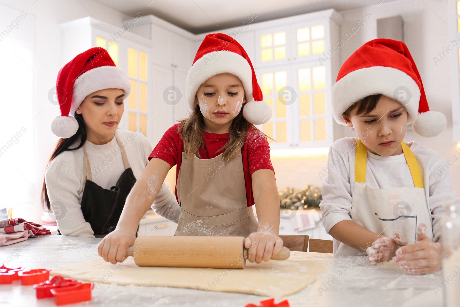 Photo of Mother and her cute little children making Christmas cookies in kitchen