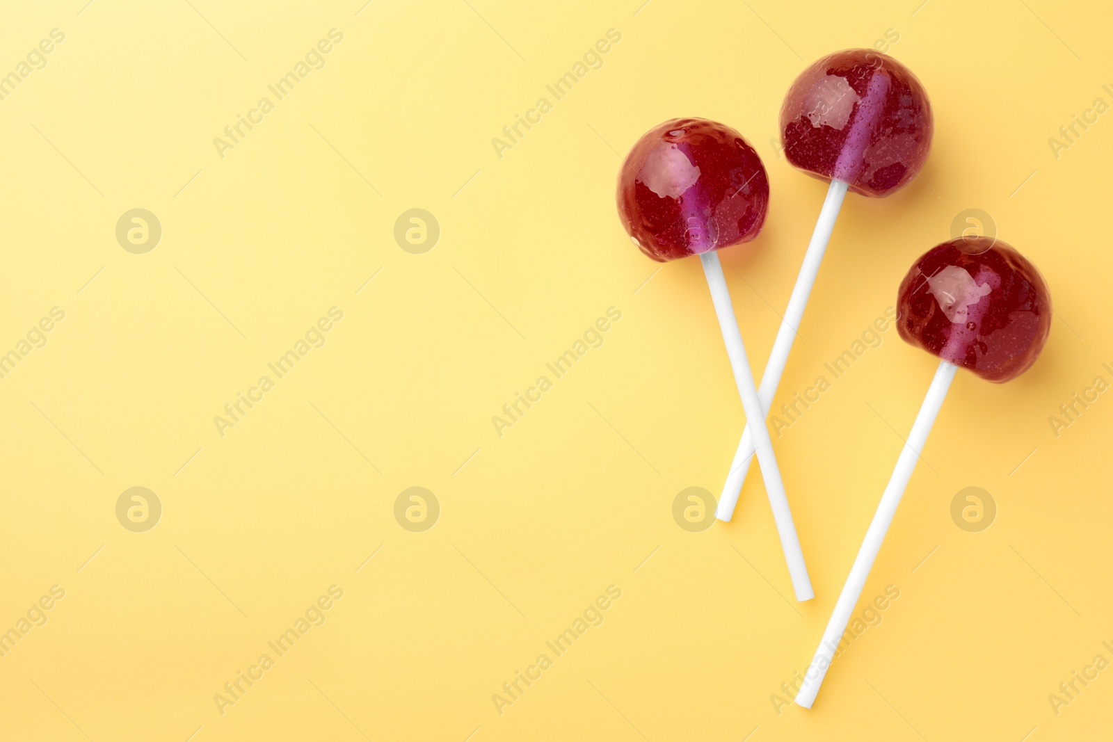 Photo of Tasty lollipops on yellow background, flat lay. Space for text