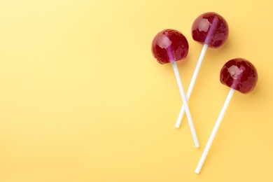 Tasty lollipops on yellow background, flat lay. Space for text