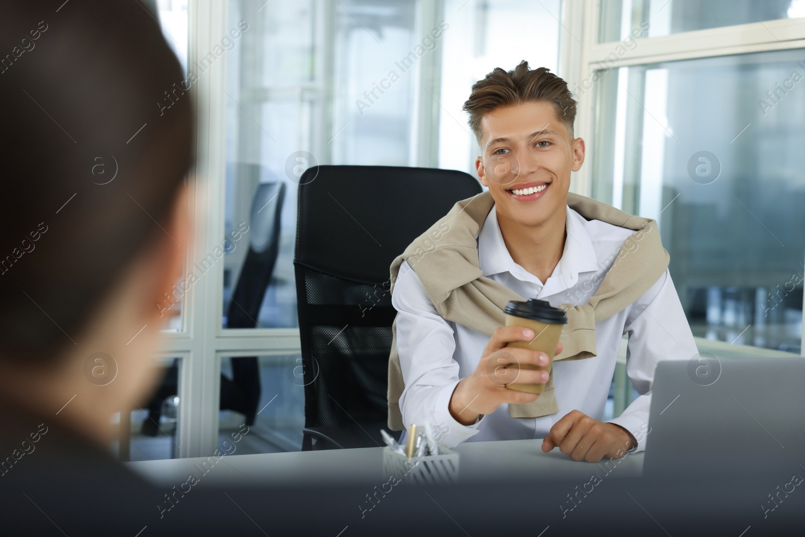 Photo of Happy man with paper cup of coffee in open plan office