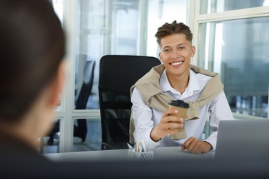 Photo of Happy man with paper cup of coffee in open plan office