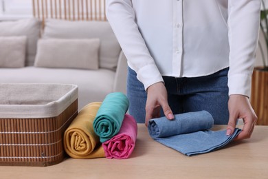 Woman rolling shirt at table in room, closeup. Organizing clothes