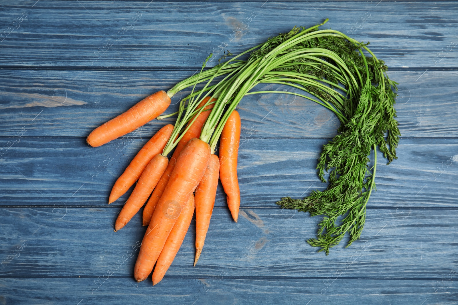 Photo of Ripe carrots on wooden background, top view