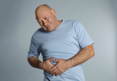 Photo of Mature man suffering from liver pain on light grey background