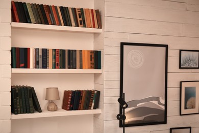 Photo of Home library interior with collection of different books on shelves and beautiful pictures