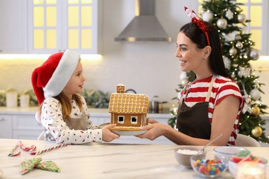 Mother and daughter with gingerbread house in kitchen