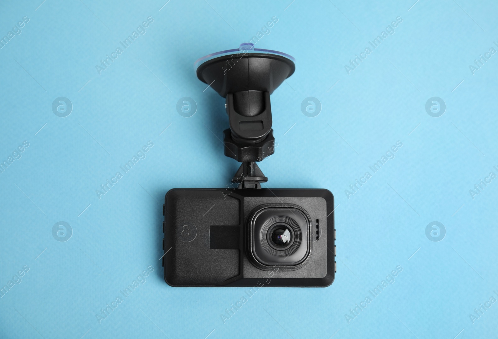 Photo of Modern car dashboard camera with suction mount on light blue background, top view