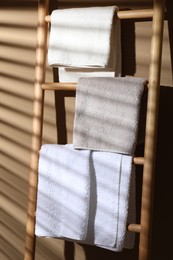 Photo of Terry towels on wooden decorative ladder near beige wall