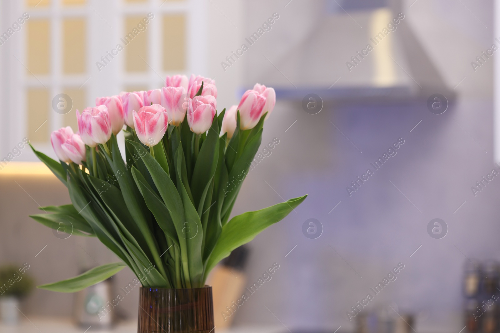 Photo of Beautiful bouquet of fresh pink tulips in kitchen. Space for text