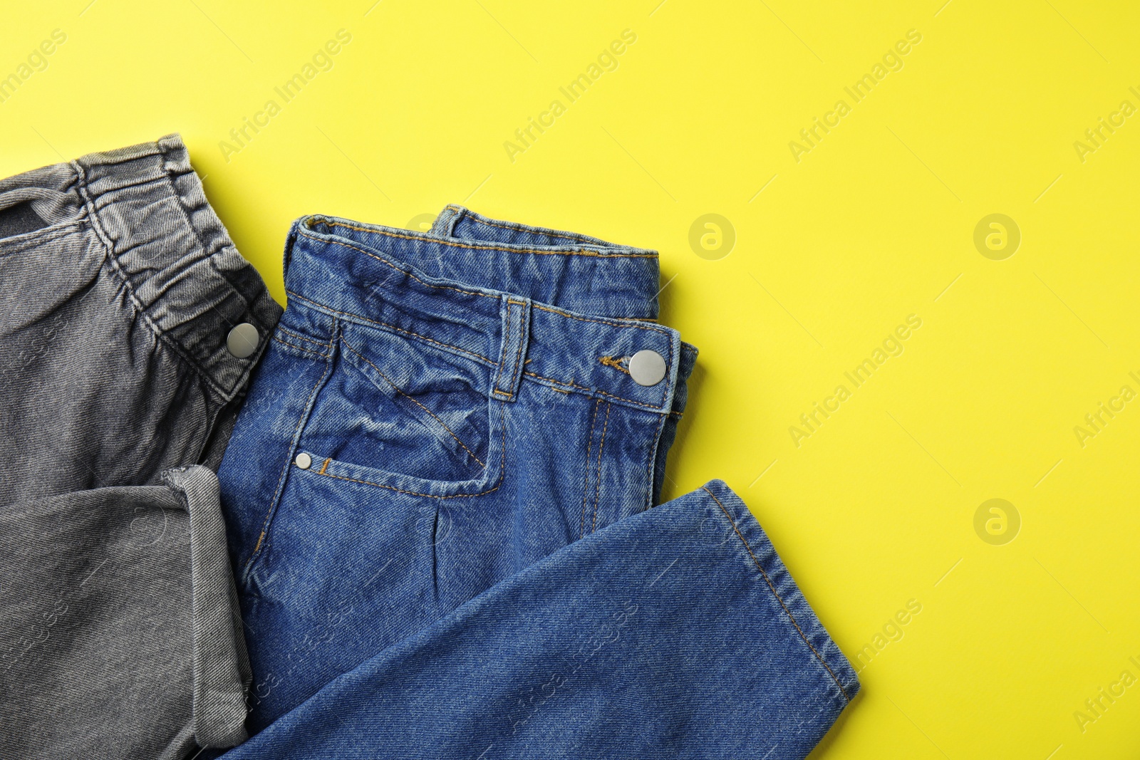 Photo of Stylish jeans on yellow background, top view