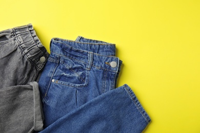 Photo of Stylish jeans on yellow background, top view