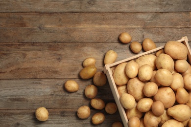 Photo of Raw fresh organic potatoes on wooden background, top view. Space for text