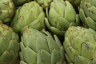 Many fresh raw artichokes as background, closeup