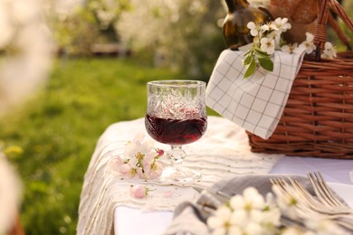 Stylish table setting with beautiful spring flowers and wine in garden