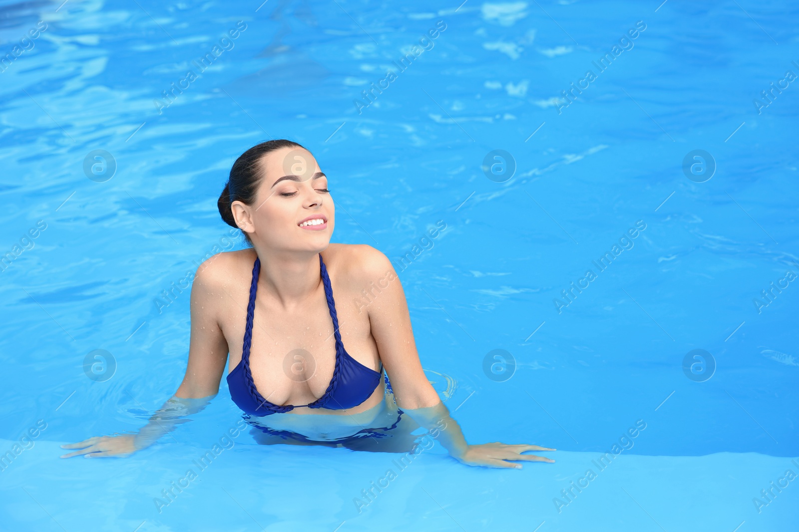 Photo of Beautiful young woman wearing bikini in blue swimming pool