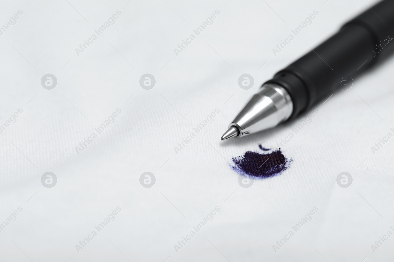 Photo of Pen and stain of black ink on white shirt, closeup. Space for text