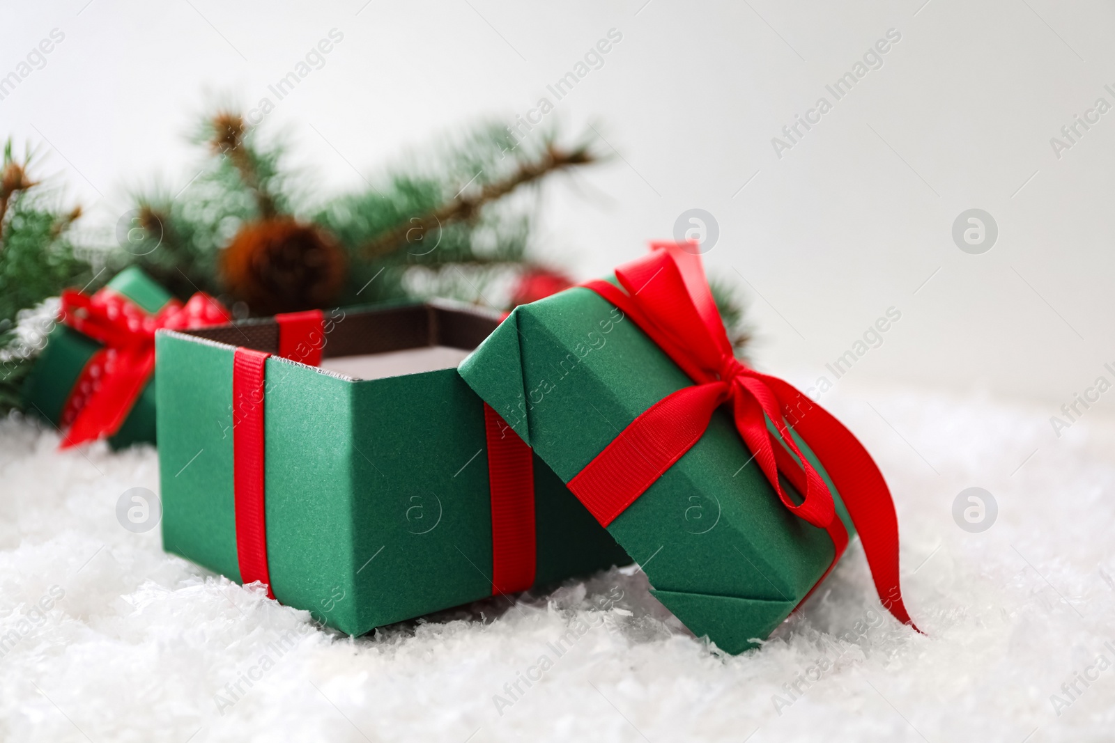 Photo of Open Christmas gift box with red bow on snow