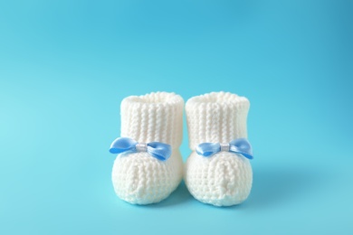 Photo of Handmade baby booties with bows on color background