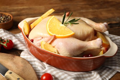 Photo of Chicken with orange slices and other ingredients on wooden table