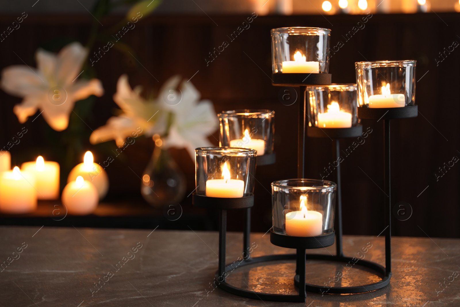 Photo of Holder with burning candles on table in darkness, space for text. Funeral symbol