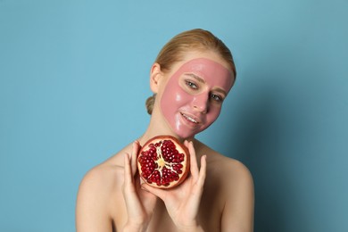 Young woman with pomegranate face mask and fresh fruit on light blue background