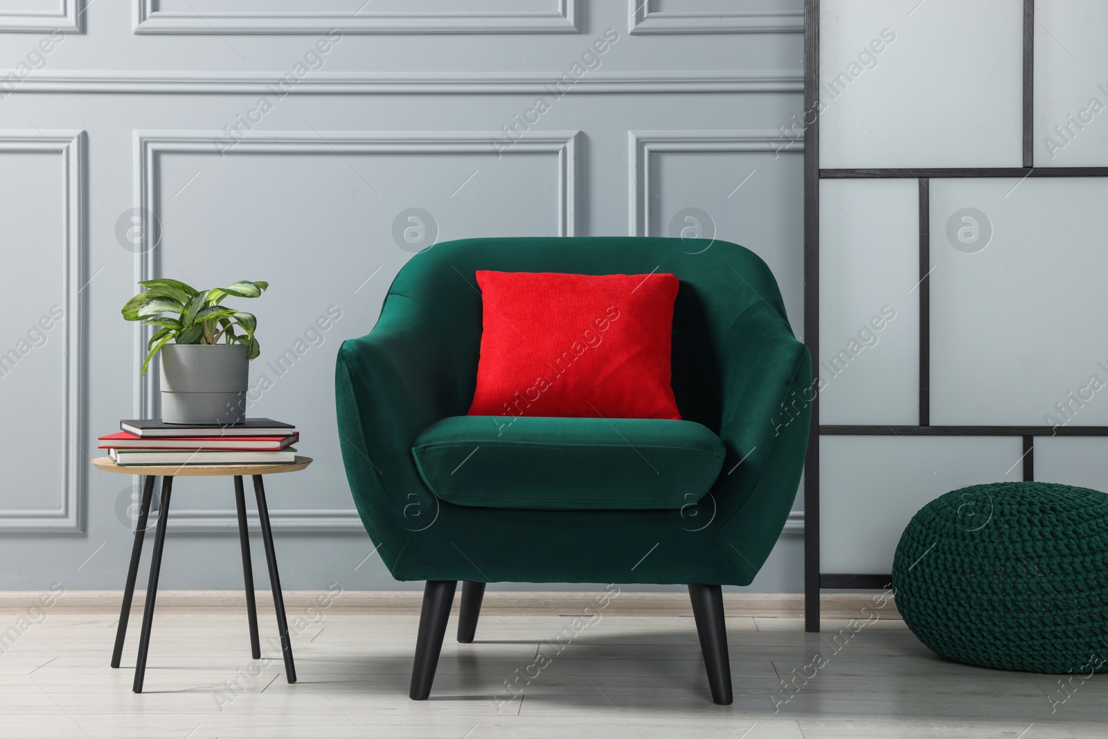 Photo of Stylish armchair and side table with houseplant near light grey wall indoors. Interior design