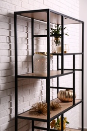 Photo of Shelving with different decor near white brick wall. Interior design