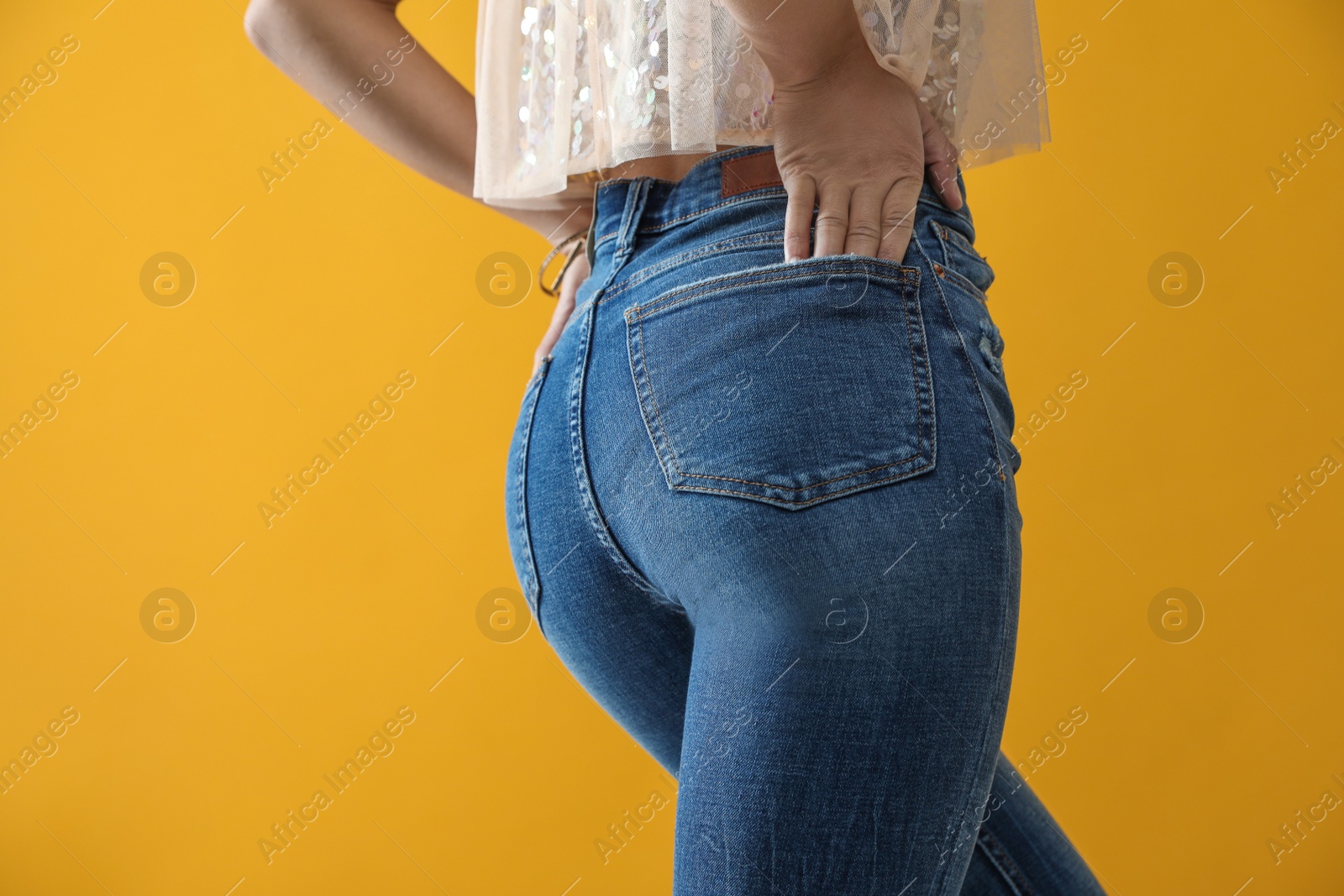 Photo of Woman wearing jeans on yellow background, closeup