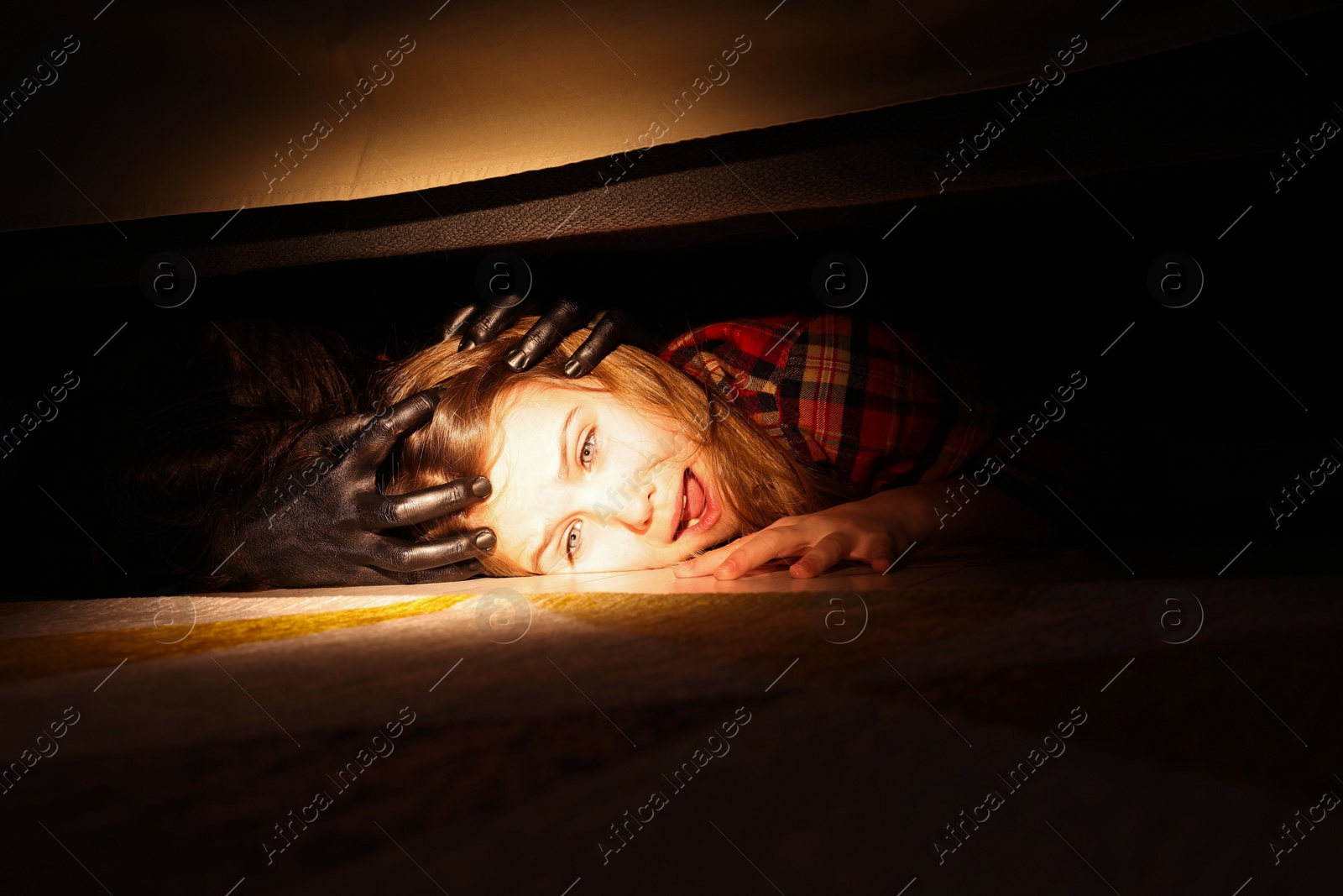 Photo of Childhood phobia. Little girl with monster under bed at home, closeup