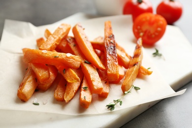 Board with sweet potato fries on grey table, closeup