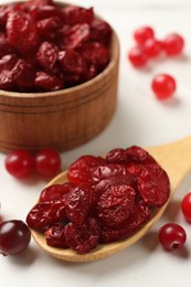 Tasty dried cranberries and fresh ones on white table, closeup