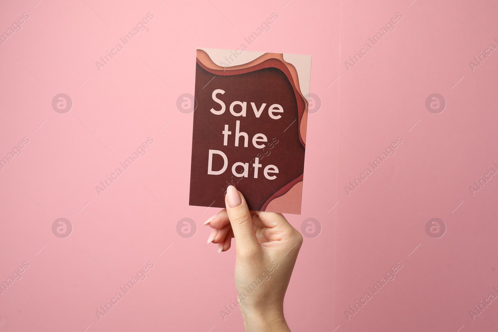 Photo of Woman holding beautiful card with Save the Date phrase on pink background, closeup