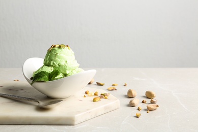 Photo of Tasty pistachio ice cream served on grey table against light background, space for text