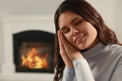 Photo of Young woman resting near fireplace at home, closeup