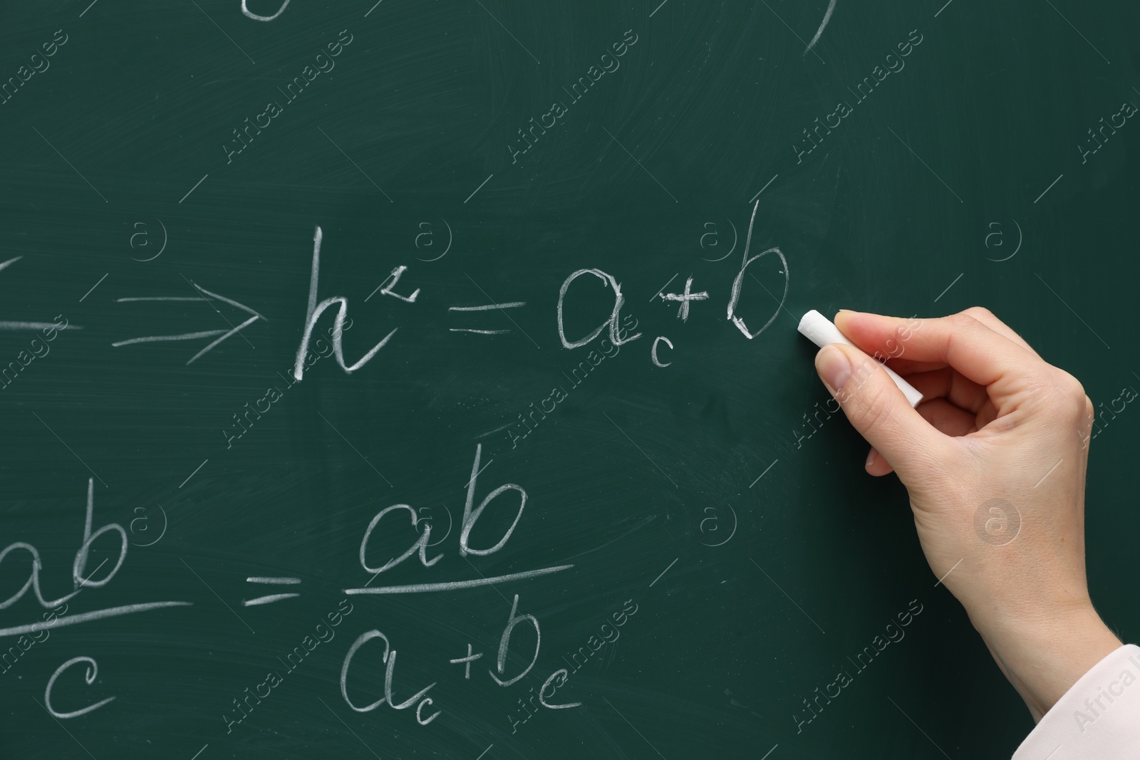 Photo of Teacher writing down math equation on green board, closeup