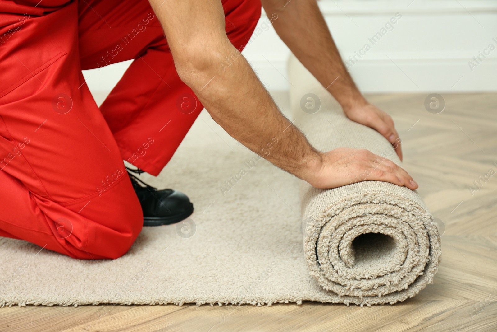 Photo of Worker rolling out new carpet flooring indoors, closeup