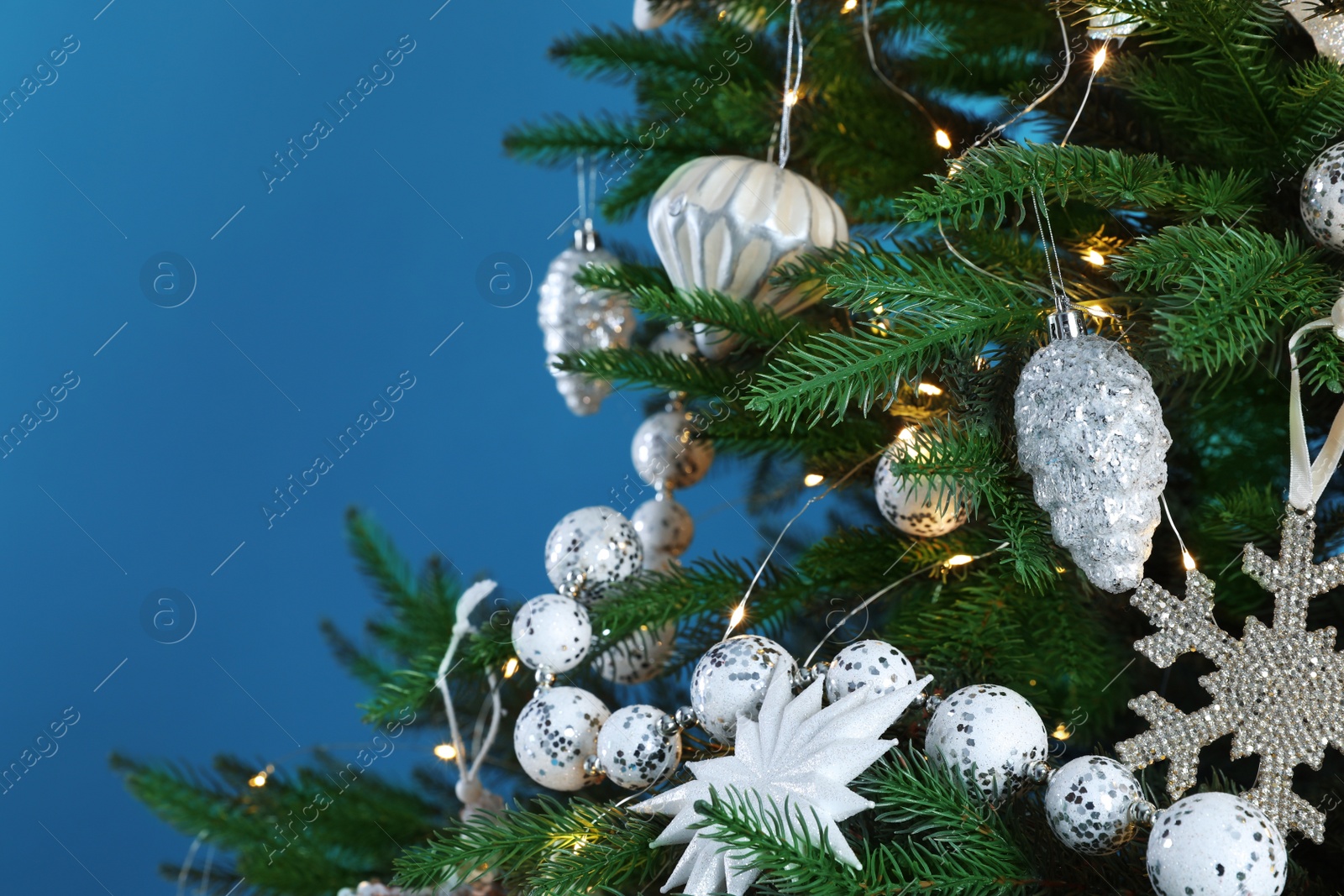 Photo of Beautiful Christmas tree with decor on light blue background, closeup. Space for text