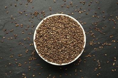 Ceramic bowl with chia seeds on black table, flat lay. Cooking utensil