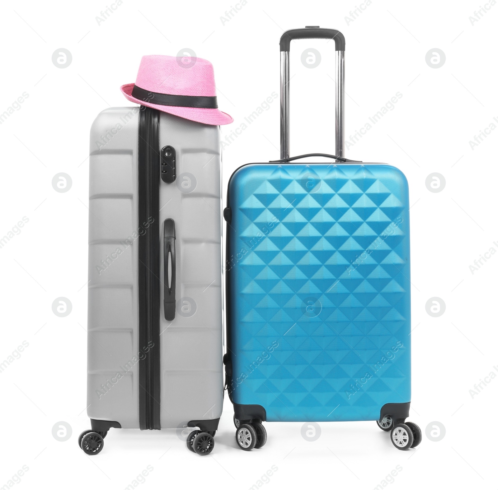 Photo of New suitcases and hat packed for journey on white background