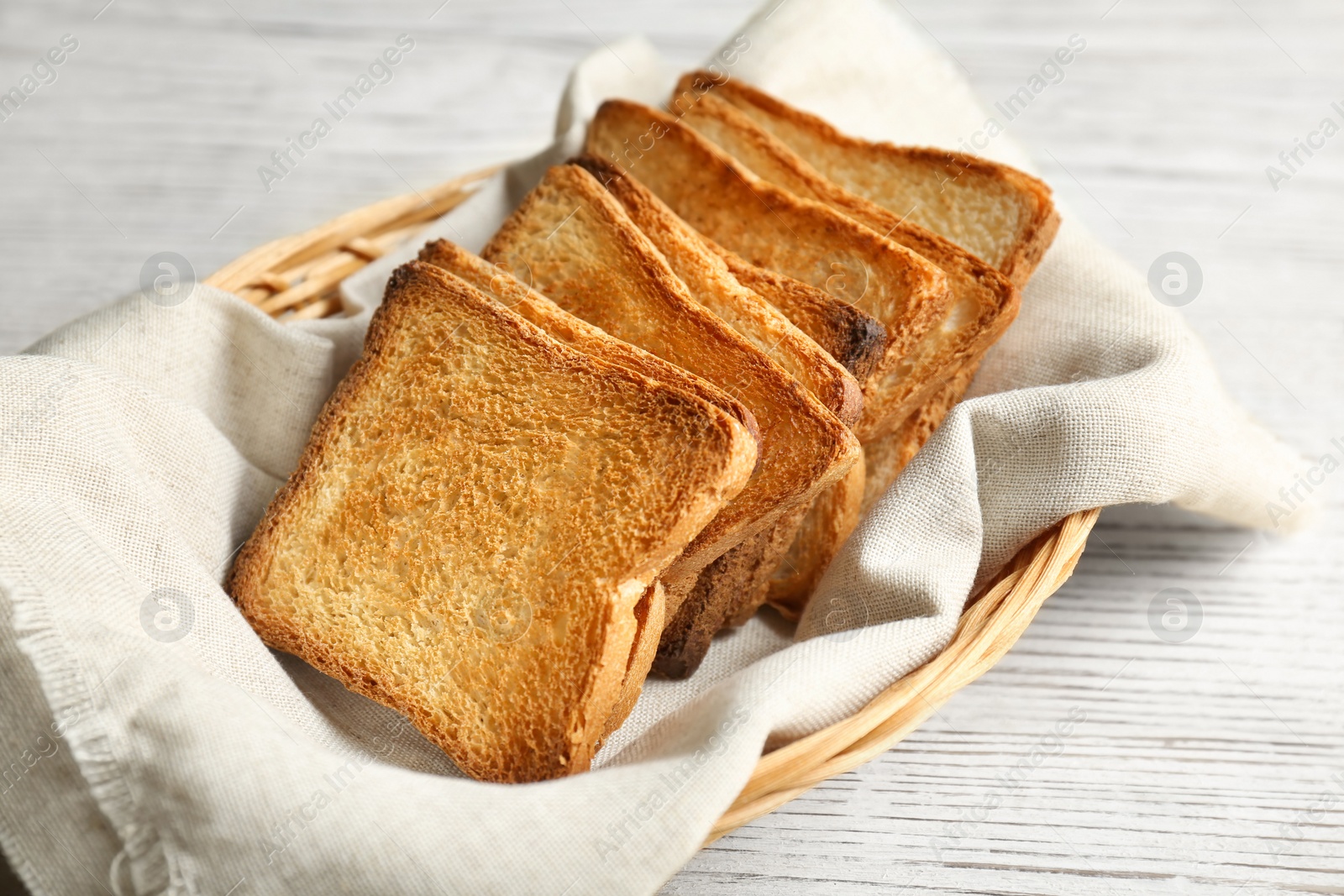 Photo of Basket with toasted bread on wooden table