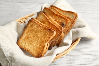 Photo of Basket with toasted bread on wooden table