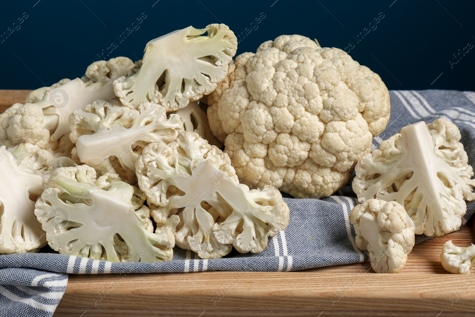 Photo of Cut and whole cauliflower on wooden tray