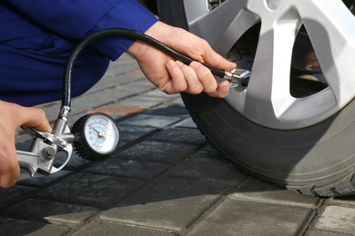 Photo of Mechanic checking tire air pressure at car service, closeup