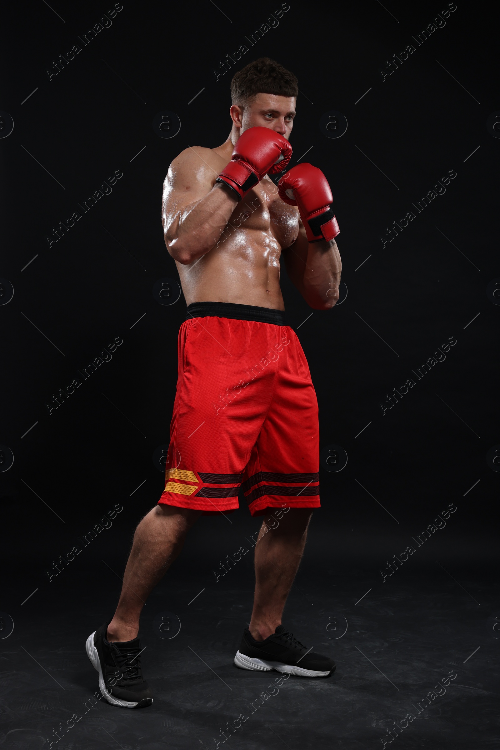 Photo of Man in boxing gloves on black background