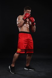 Photo of Man in boxing gloves on black background