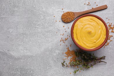 Photo of Bowl with delicious mustard, seeds and dry thyme on light grey table, flat lay. Space for text