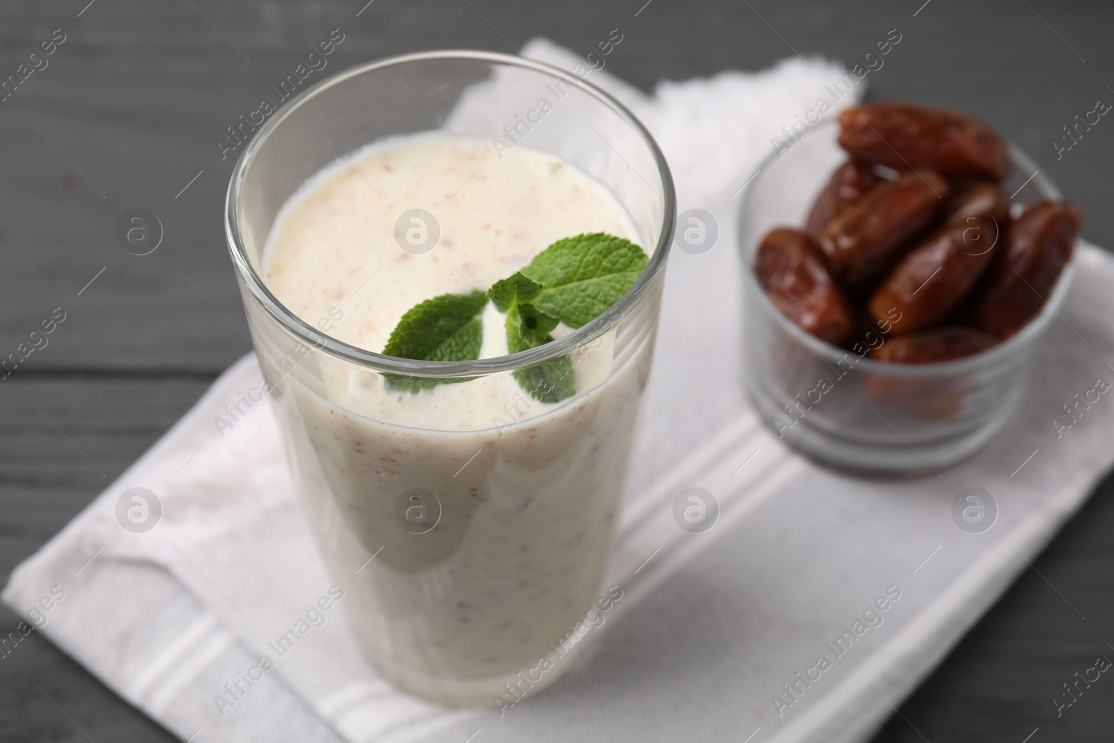 Photo of Glass of delicious date smoothie with mint and dried fruits on grey table, closeup. Space for text