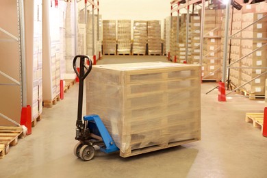 Modern manual forklift with wrapped wooden pallets in warehouse