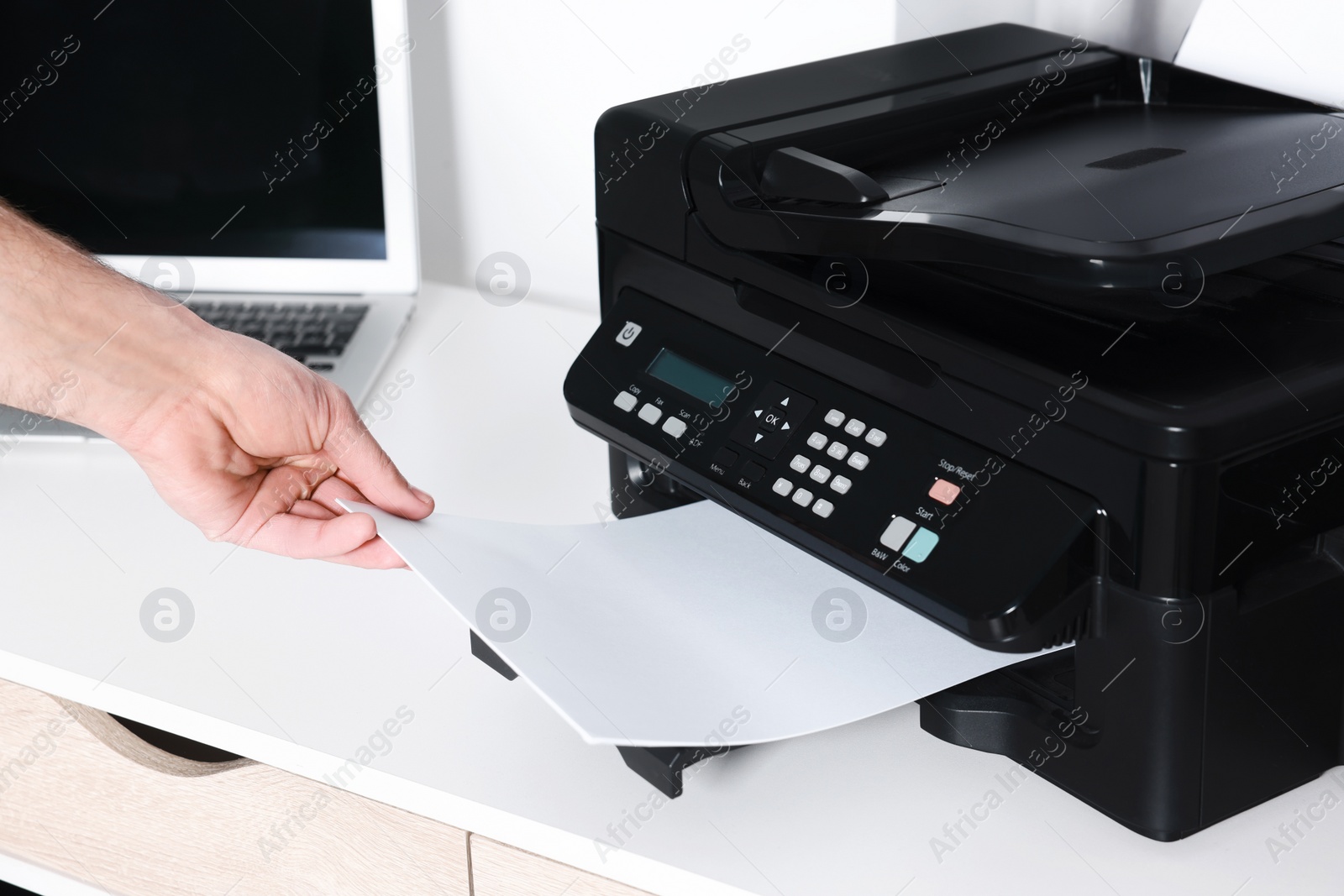 Photo of Man using modern printer at white desk in office, closeup