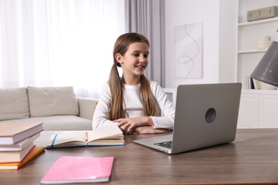 E-learning. Cute girl using laptop during online lesson at table indoors